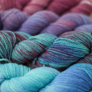 A close-up of variegated yarn in shades of turquoise, purple, blue and pink