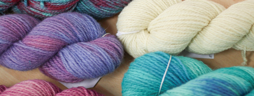 Five skeins of variegated yarn, in shades of pink, purple and turquoise, and natural cream