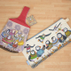 a wrist project bag with watercolour sheep, and a long zipped project bag with watercolour puffins, both flat on a countertop