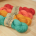 4 skeins of differently coloured mohair-wool blend yarn, (green, orange, coral and red), lying flat on a counter